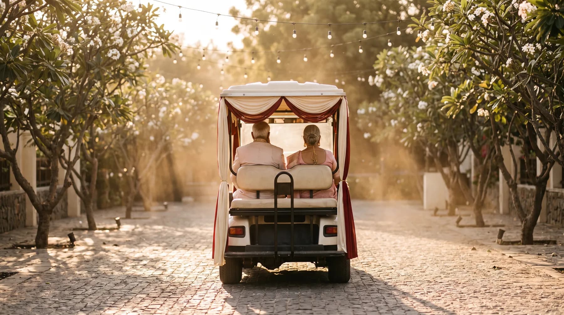 A golf cart carrying guests along a resort path at golden hour